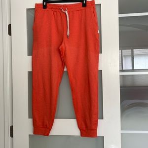 Vuori orange performance jogger. Relaxed fit. Tapered leg. Cuff above ankle. Lge